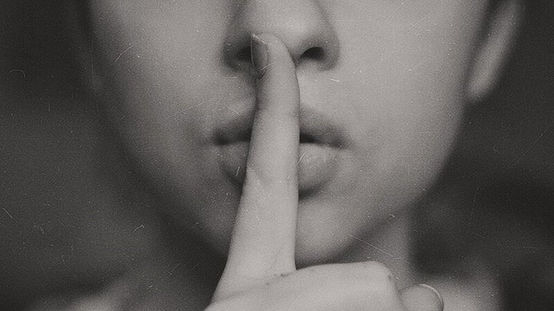 black and white image of woman with shush finger on her lips