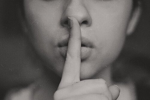 black and white image of woman with shush finger on her lips